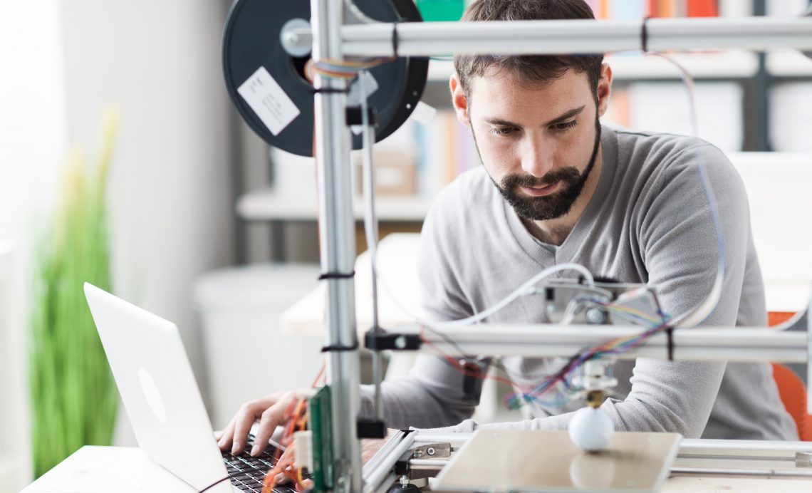 Young designer engineer using a 3D printer in the laboratory and studying a product prototype, technology and innovation concept