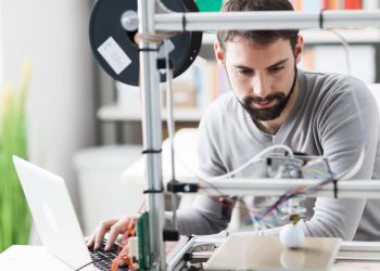 Young designer engineer using a 3D printer in the laboratory and studying a product prototype, technology and innovation concept