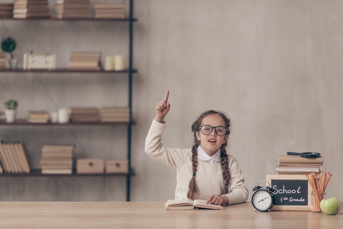 Happy little pupil with a book in studio