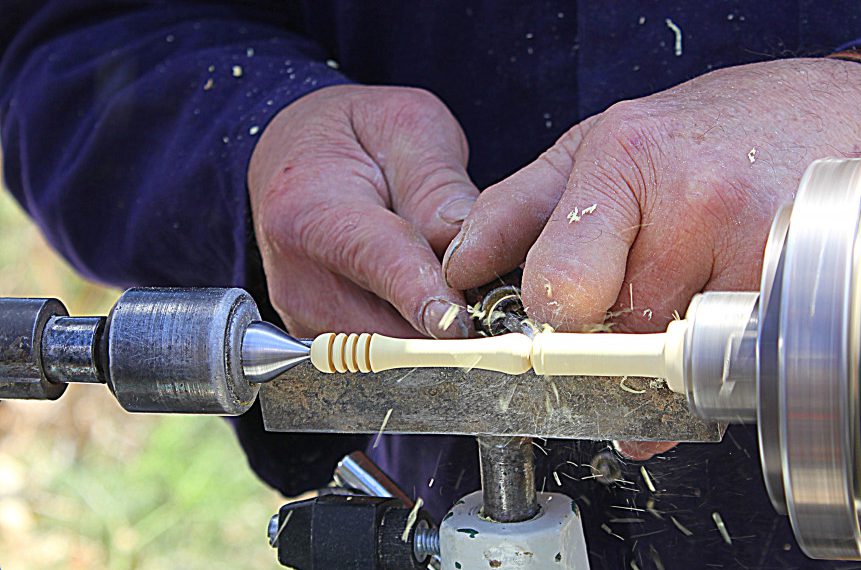 Man chiseling off material on a lathe